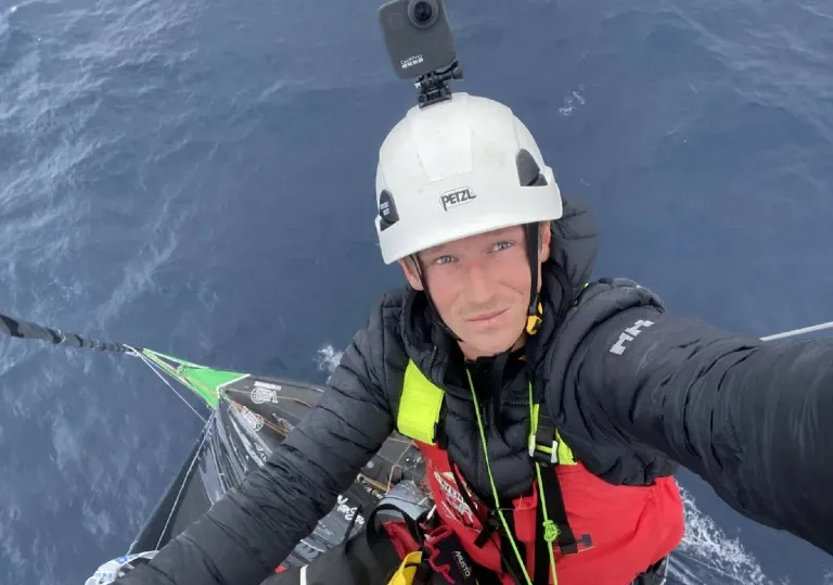 Skipper de face. Il est monté au mât du bateau